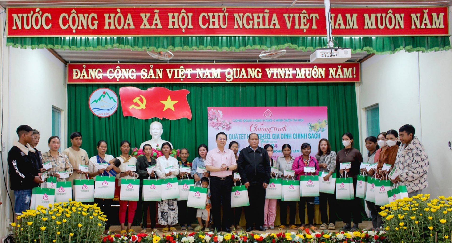 Ông Nguyễn Hữu Quang (áo hồng - giữa) - Phó Giám đốc NHCSXH và ông Liêng Hột Ha Hai - Phó Chủ tịch UBND huyện Đam Rông trao quà Tết cho các hộ gia đình ở huyện Đam Rông