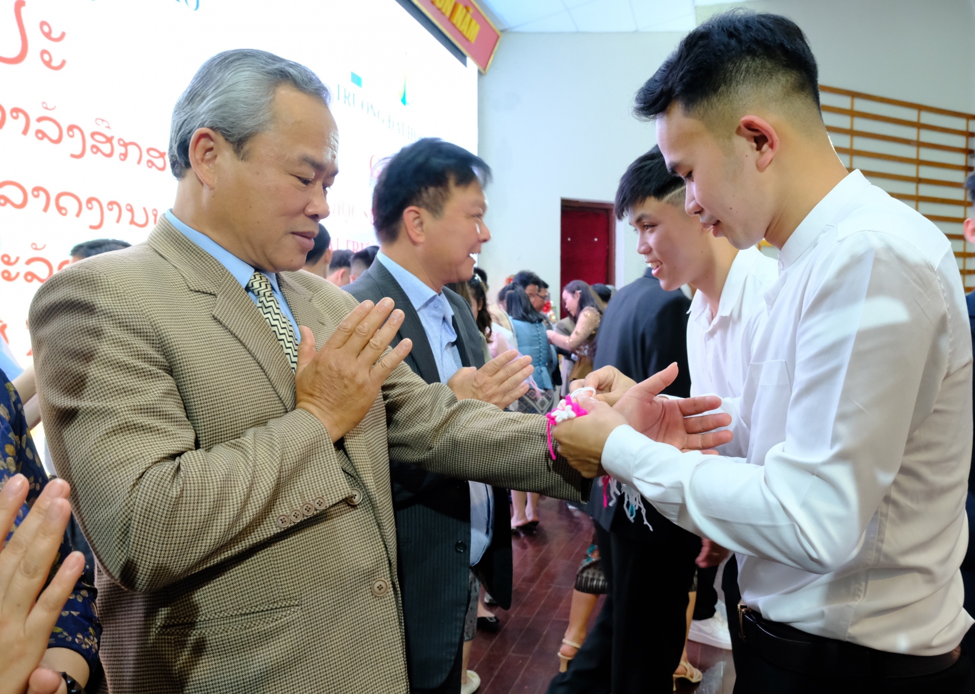 Lưu học sinh Lào thực hiện nghi thức buộc chỉ tay cùng lời chúc may mắn đến các đại biểu