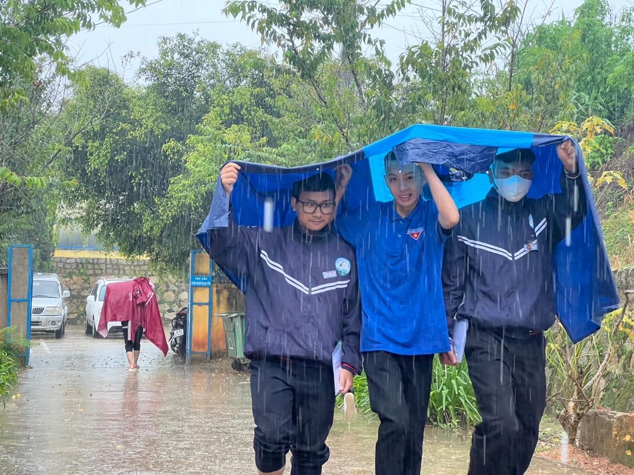 Đội hình tiếp sức mùa thi hỗ trợ thí sinh đến làm thủ tục dự thi chiều 26/6 trong cơn mưa tầm tã