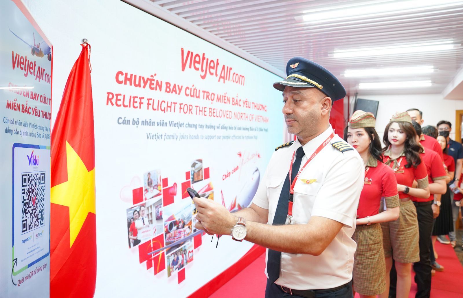 Cán bộ, nhân viên Vietjet tranh thủ quét QR code ngay tại sân đỗ, dưới trời mưa để ủng hộ người dân vùng bão lũ