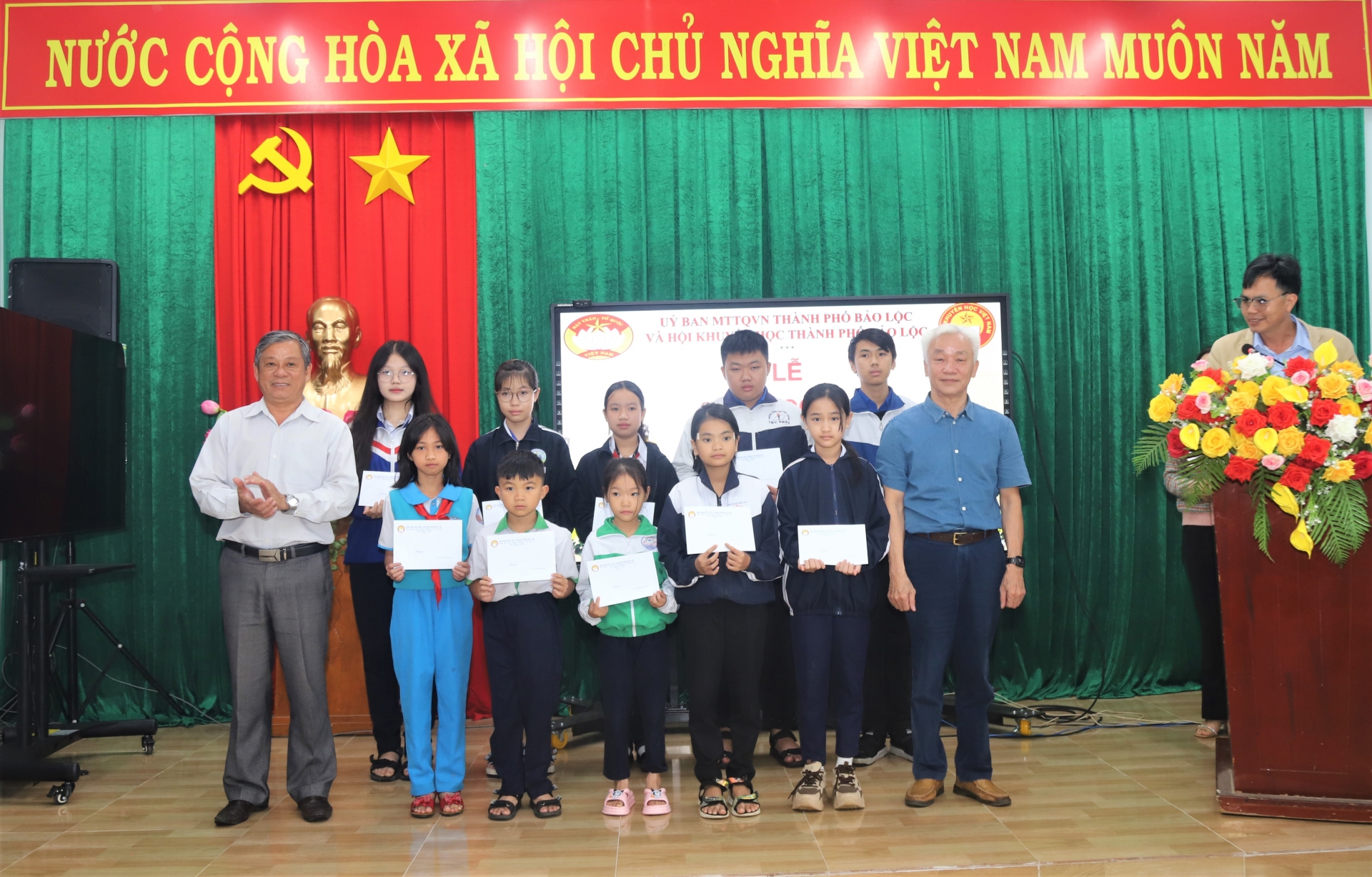 Ông Dương Kim Viên - Chủ tịch Hội Khuyến học TP Bảo Lộc cùng đại diện Ban Tuyên giáo Thanh ủy Bảo Lộc trao tặng học bổng cho các em học sinh nghèo vượt khó học giỏi