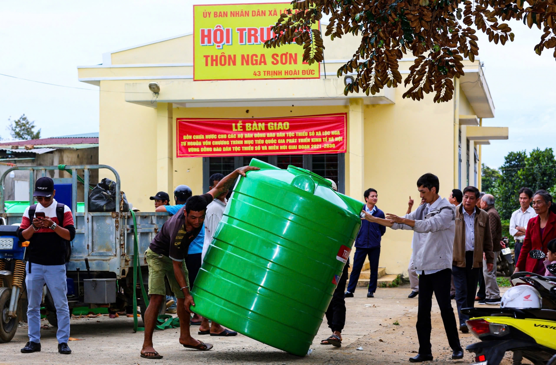 Bà con đồng bào tiếp nhận bồn chứa nước được cấp phát miễn phí theo Chương trình mục tiêu Quốc gia