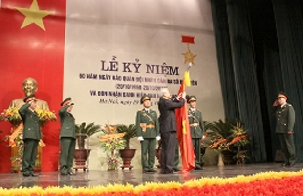 Chủ tịch Quốc hội Nguyễn Phú Trọng gắn huy hiệu Anh hùng Lao động lên lá cờ Quyết thắng Báo Quân đội Nhân dân.