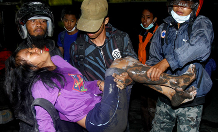 Người dân trong làng Klaten gần núi lửa Merapi khiêng một phụ nữ bị thương trong lúc sơ tán tối 5/11. Ảnh: AP.