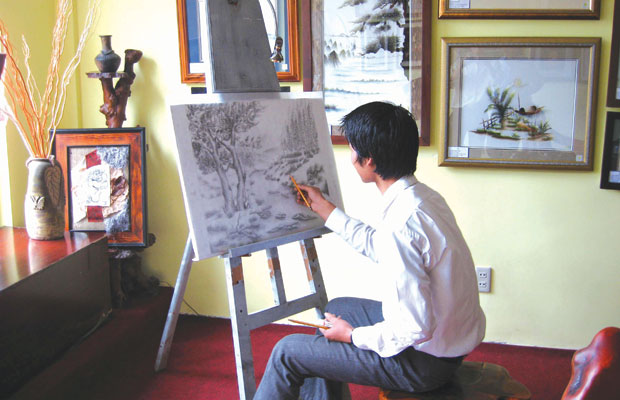 Họa sỹ Đăng Việt đang vẽ thiết kế mẫu thêu mới.