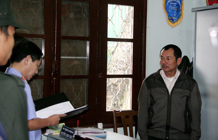 Ông Nguyễn Long Vân (bên phải) nghe cơ quan điều tra đọc lệnh khám xét tại nơi làm việc