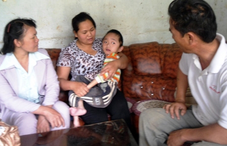 Chị Tạ Hồng Tuyết (ở giữa) bồng đứa con bệnh u não đã 8 tuổi.