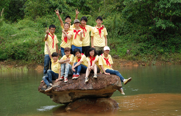 Nhóm học sinh đi tham quan Khu di tích căn cứ núi Voi chụp hình lưu niệm bên hồ núi Voi