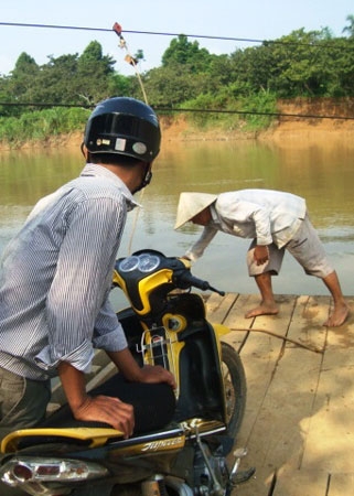 Cả xe máy và người qua sông Đạ Huoai trên một chiếc bè “tự chế”