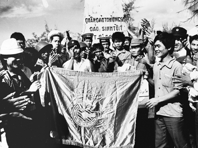 Tháng 3-1988, nhận nhiệm vụ của T.Ư Đoàn TNCS Hồ Chí Minh, PV Báo Tiền Phong (bìa trái) trao cờ Đoàn cho chiến sĩ trẻ trên đảo Sinh Tồn. Ảnh: Đình Trân.