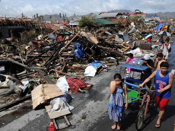 Người dân đi bên đống đổ nát sau bão Haiyan ở thành phố Tacloban, miền trung Philippines hôm 10/11. (Ảnh: AFP/TTXVN)