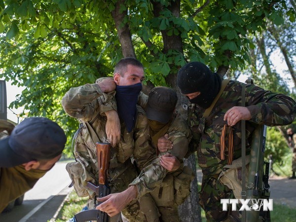 Các tay súng biểu tình hỗ trợ đồng đội bị thương trong xung đột tại Donetsk, Ukraine ngày 26/5. (Nguồn: THX/TTXVN)