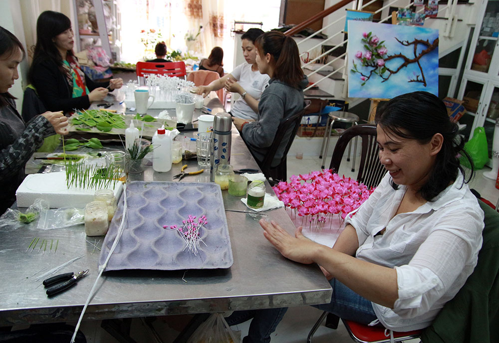 Chị Hòa (bìa phải) là một thợ làm hoa đất sét lành nghề, tự tin hướng dẫn cho những thành viên mới bắt đầu. Ảnh: H.T