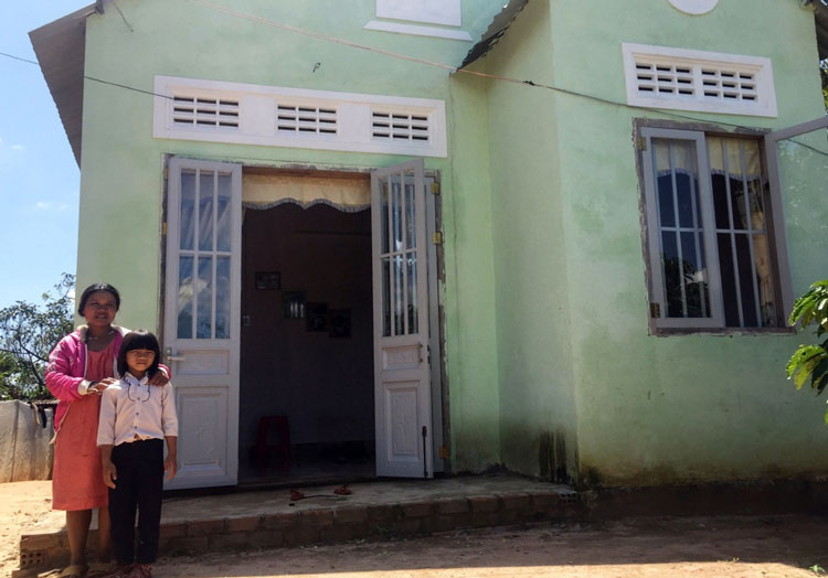 Chị Liêng Jrang K’Yên cùng con trước ngôi nhà mới xây