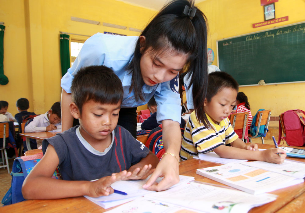Sinh viên tình nguyện Trường CĐSP Đà Lạt hỗ trợ các em học sinh vùng sâu, vùng xa tăng cường các kỹ năng đọc, viết tiếng Việt. Ảnh: Hồng Thắm