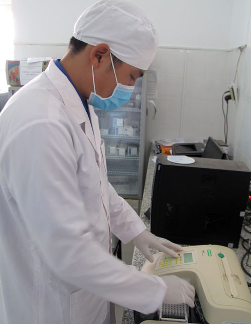 Kỹ thuật viên đưa mẫu vào máy đọc kết quả xét nghiệm tại Phòng xét nghiệm khẳng định HIV tỉnh (Trung tâm Kiểm soát bệnh tật tỉnh). Ảnh: A.Nhiên