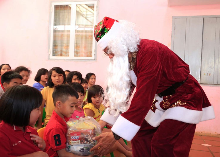 Nhạc sĩ Lê Huy Cầm hóa trang thành ông già Noel cùng các học trò biểu diễn cho trẻ em mồ côi ở Tà Nung. Ảnh: Trương Ngọc Thụy