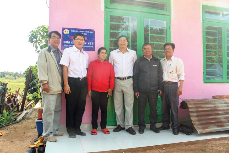 Chị Lơ Mu Mỹ Kiều (thôn Srê Đăng, xã N’Thol Hạ) chụp hình kỷ niệm cùng lãnh đạo UBMTTQVN huyện,đơn vị tài trợ trước căn nhà đại đoàn kết vừa được trao tặng