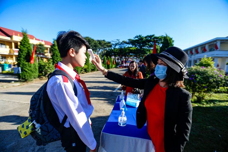 Học sinh dự lễ khai giảng được các giáo viên Trường THCS Lê Hồng Phong kiểm tra thân nhiệt, phát khẩu trang và yêu cầu rửa tay bằng nước sát khuẩn trước khi vào trường