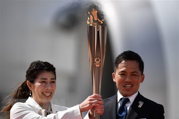 Vận động viên Nhật Bản ba lần giành Huy chương Vàng Olympic Saori Yoshida (trái) và Tadahiro Nomura (phải) giơ cao ngọn đuốc Olympic Tokyo 2020 sau khi đuốc được chuyển về từ Hy Lạp, tại căn cứ không quân Matsushima ở Higashimatsushima, tỉnh Miyagi ngày 20/3/2020