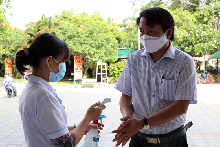 Nhân viên y tế kiểm tra thân nhiệt và sát khuẩn tay cho cử tri tham gia hội nghị tiếp xúc cử tri tại huyện Đạ Tẻh