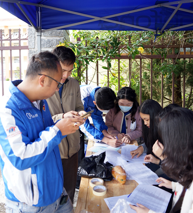 Tại cổng điểm thi, lực lượng thanh niên tình nguyện và nhân viên bảo vệ rà soát thí sinh chưa có mặt để gọi điện hỗ trợ